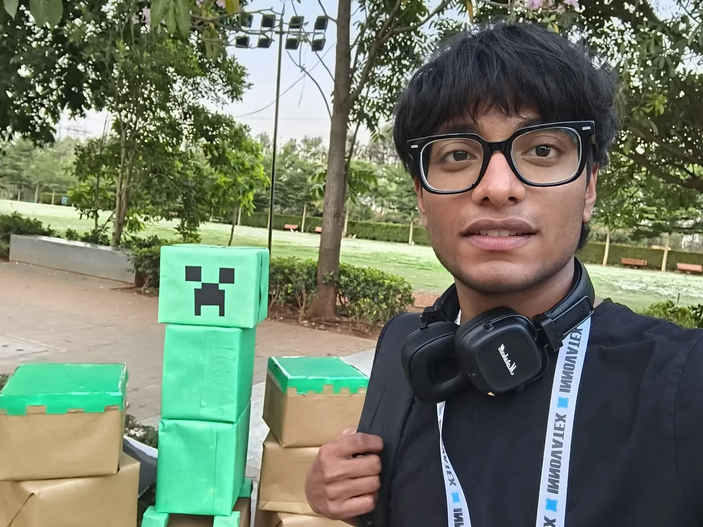 Selfie of Sonu Kumar Suman at a college tech fest beside a Minecraft Creeper built from boxes