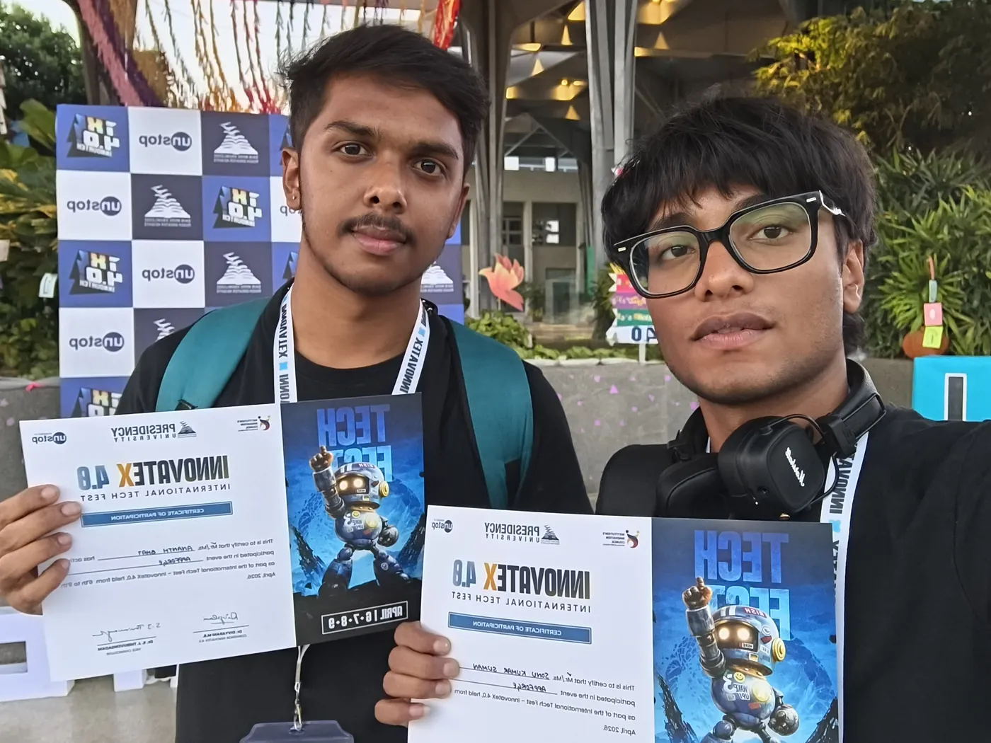 Sonu Kumar Suman and a teammate holding participation certificates in front of a sponsor backdrop