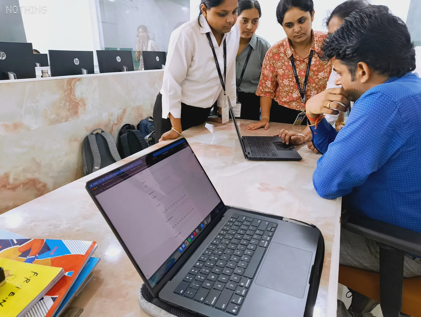 Students gathered around a laptop during a project demonstration in a lab