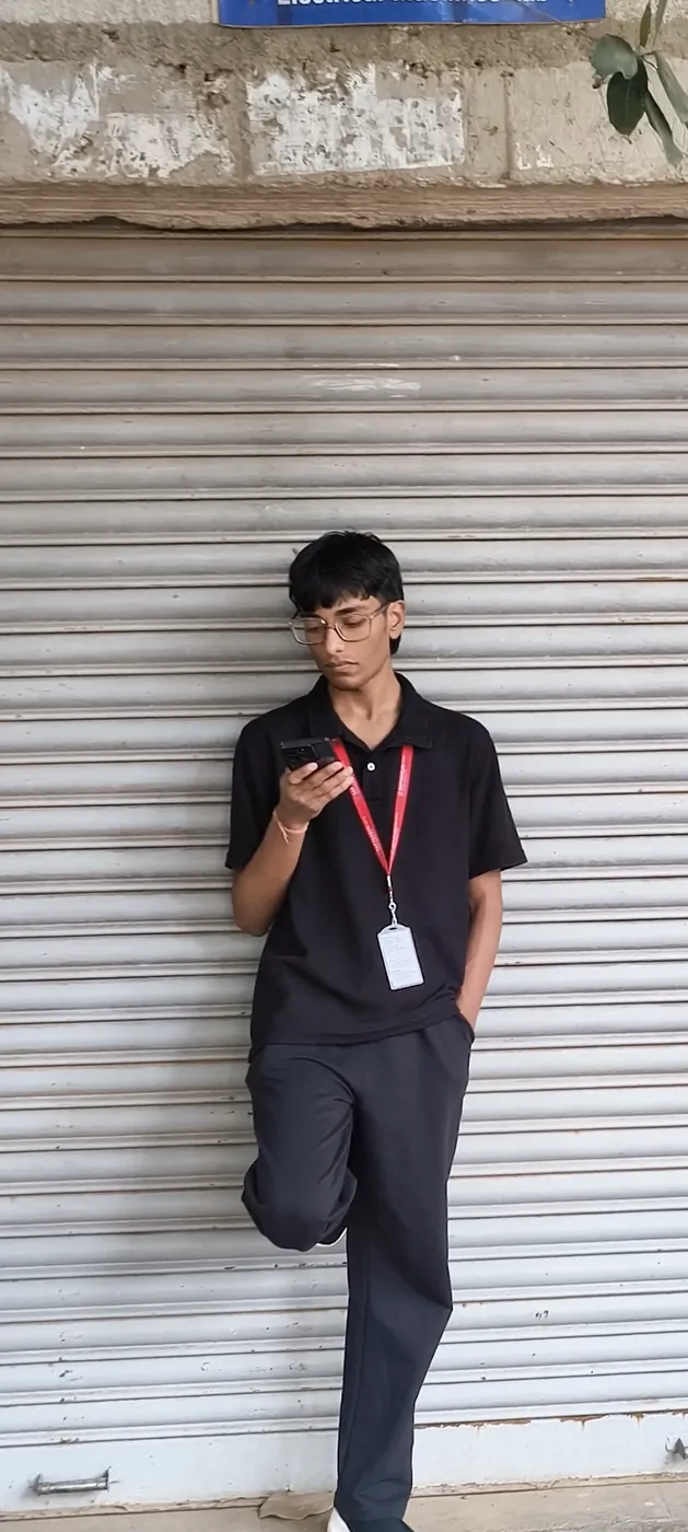 Sonu Kumar Suman leaning against a shop shutter, looking at his phone