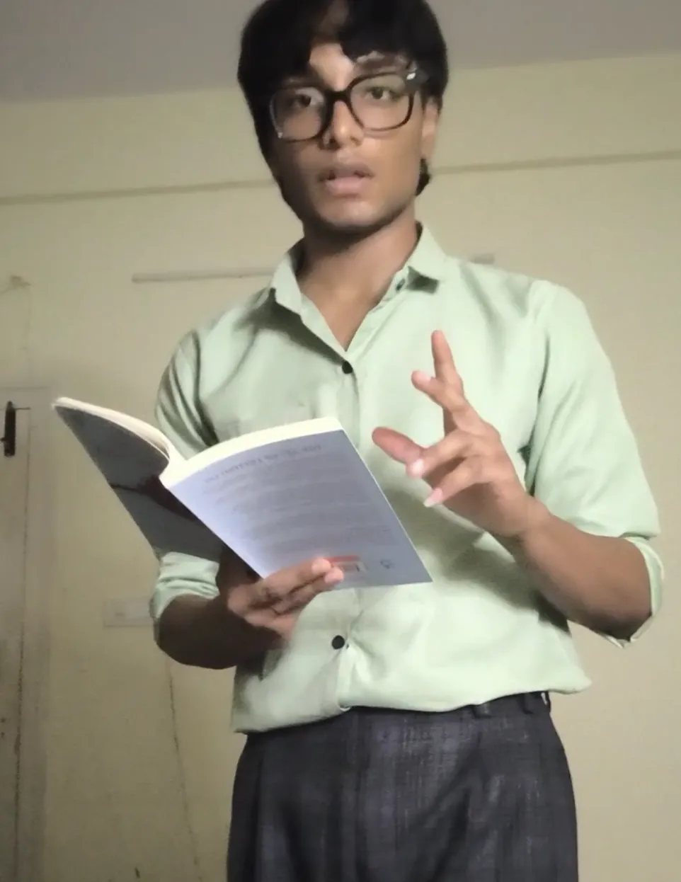 Sonu Kumar Suman in a green shirt holding an open book and gesturing while he reads