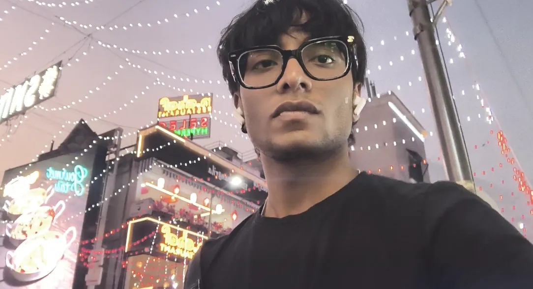 Selfie of Sonu Kumar Suman at night in front of buildings covered in festive lights