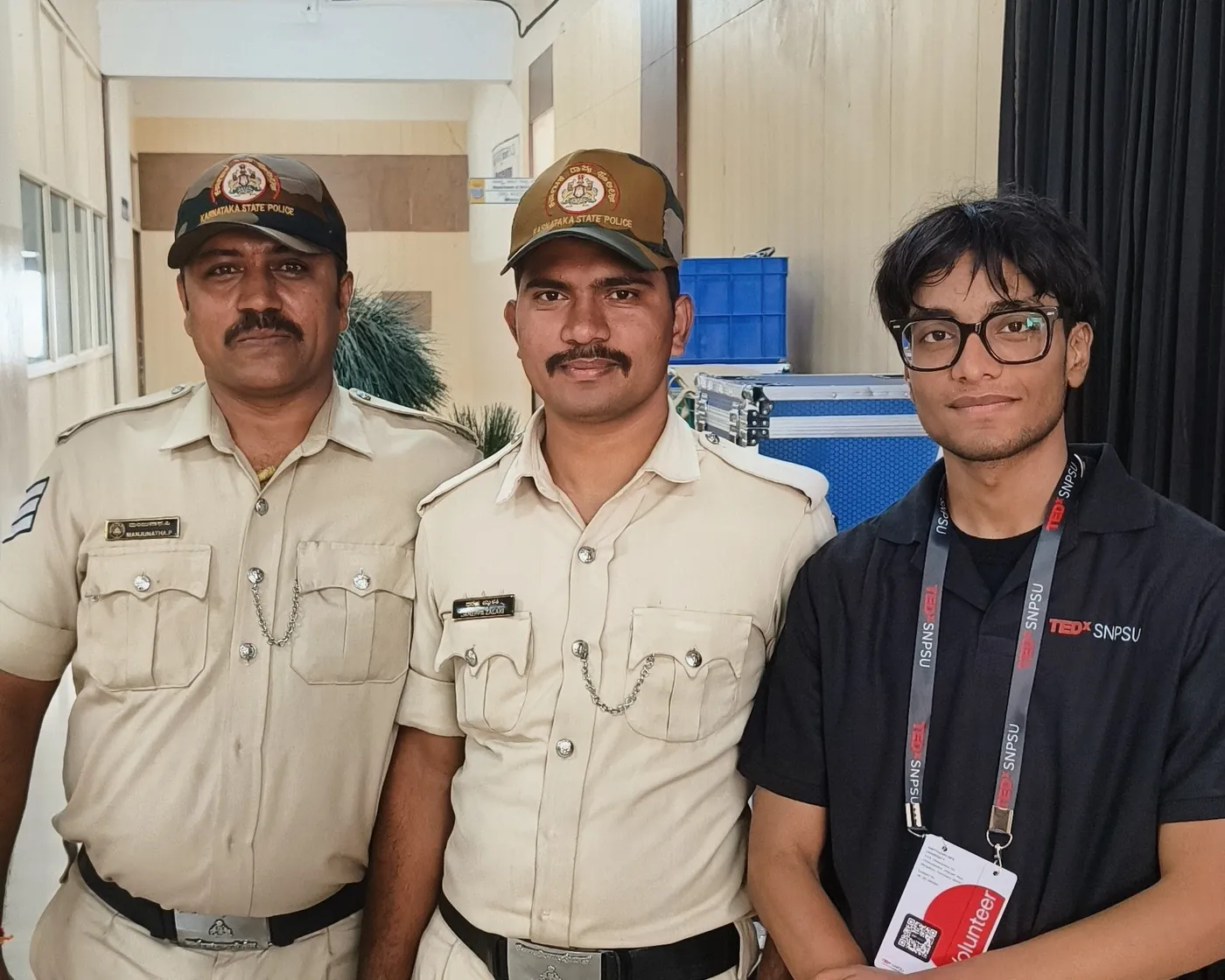 Sonu Kumar Suman in a TEDxSNPSU polo standing with two uniformed security officers