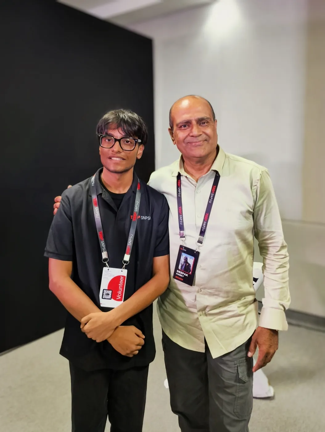 Sonu Kumar Suman in a TEDxSNPSU polo standing beside a guest wearing an event lanyard